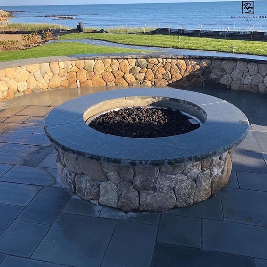 Outdoor fireplace featuring Old New England Rounds overlooking the ocean in Cape Cod.
